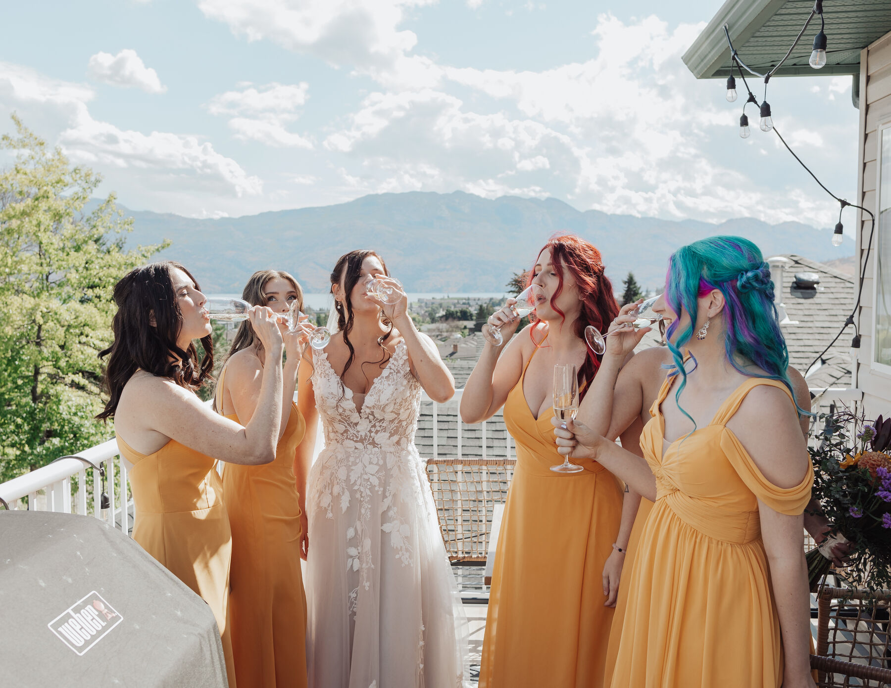 Bridal party toasting with champagne on a balcony above the lake